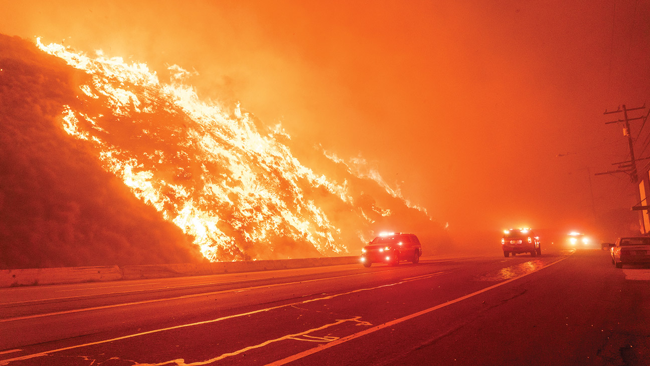 Emergency workers drive past the Palisades Fire in the Pacific Palisades neighborhood of Los Angeles, California, US, on Tuesday, Jan. 7, 2025.