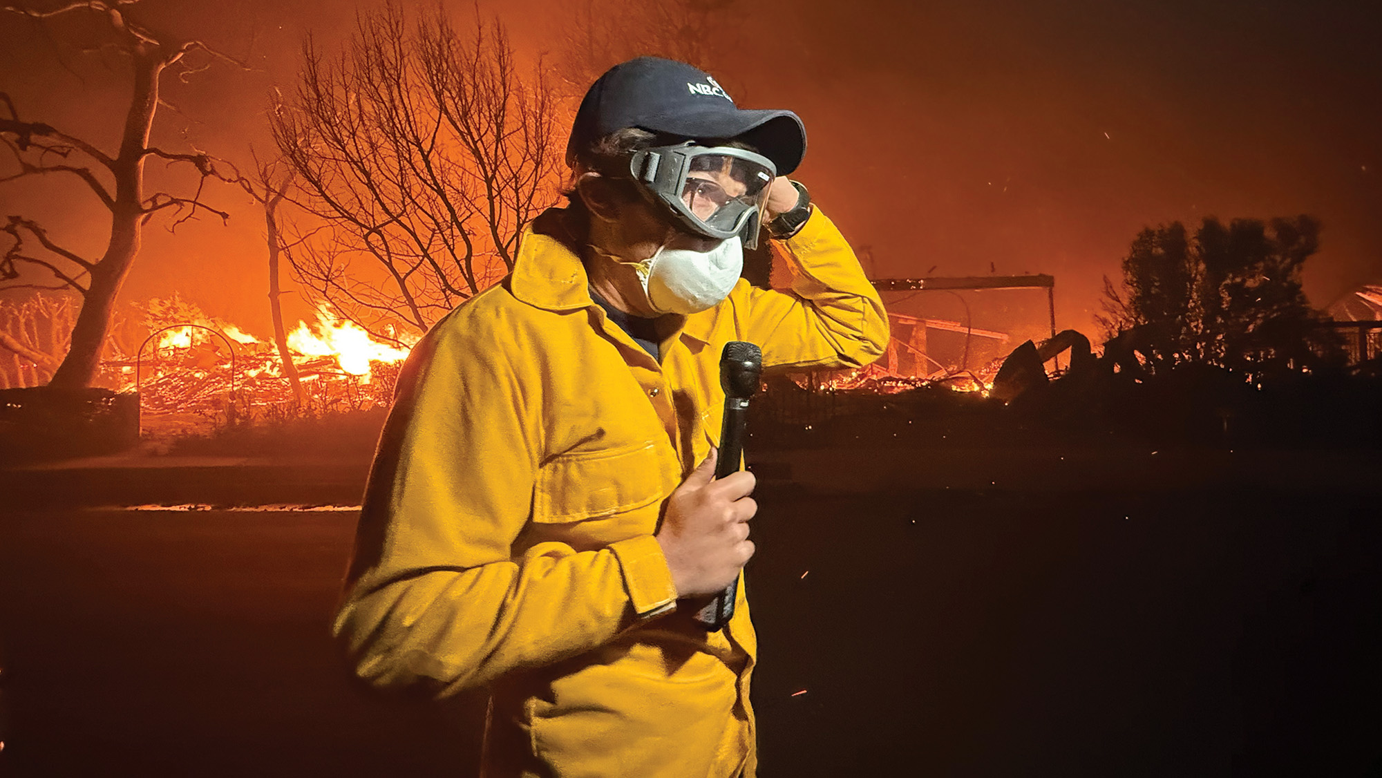 Jacob Soboroff in a yellow jacket and N95 protective mask in front of a fire during the Palisades fire