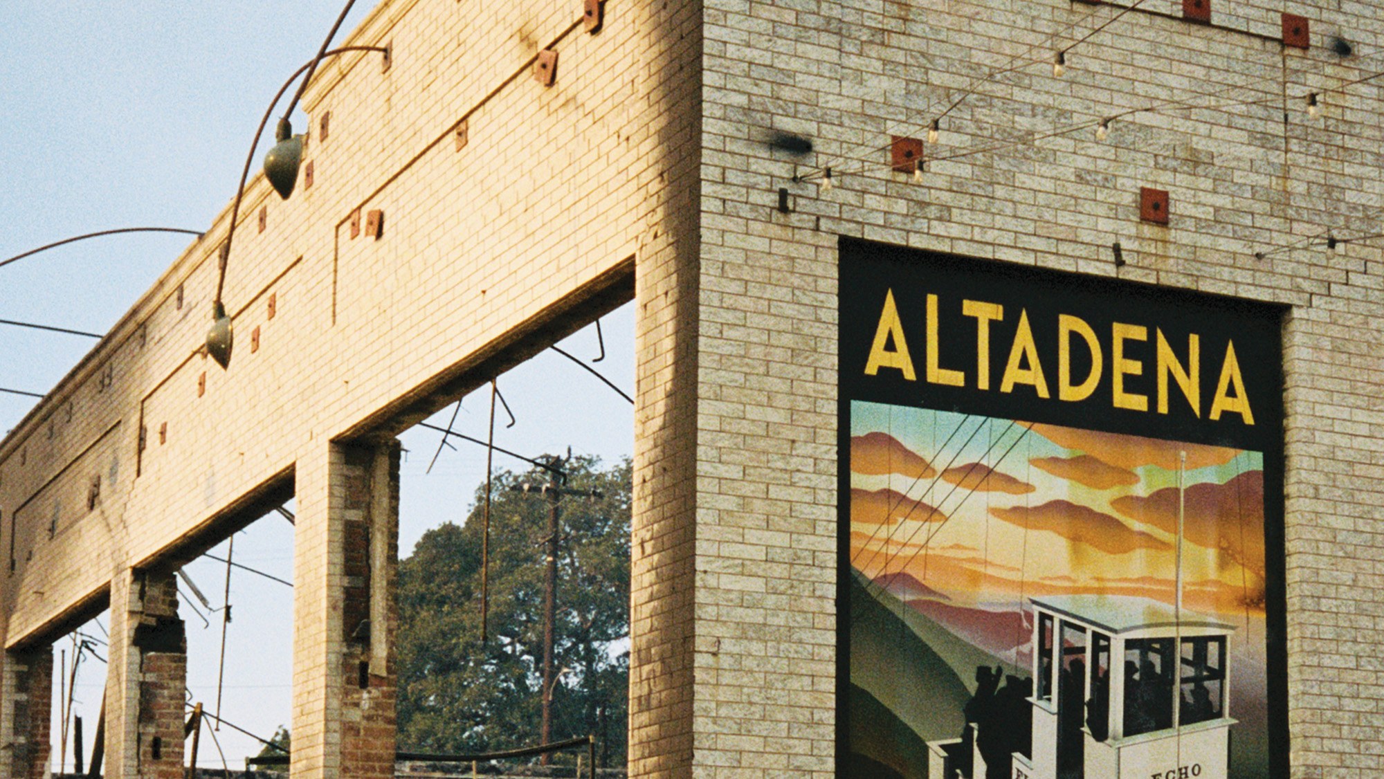 An 'Altadena' poster on the wall of an otherwise burned down brick building